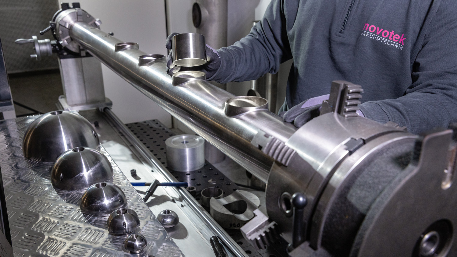 EN Mitarbeiter in Werkstatt steht an Maschine zum Aushalsen