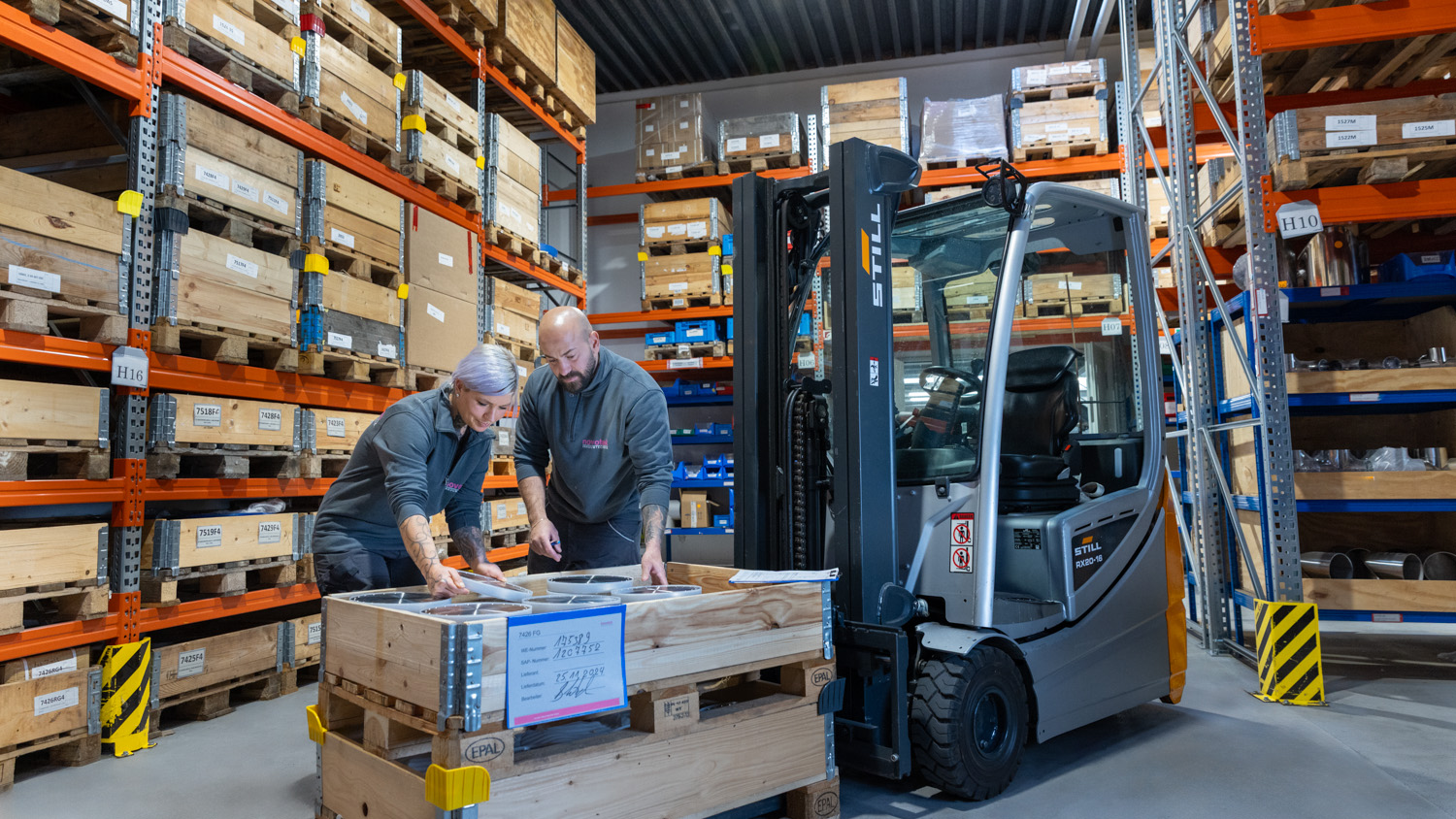 Mitarbeiter:innen im Lager beladen Paletten auf einem Gabelstabler