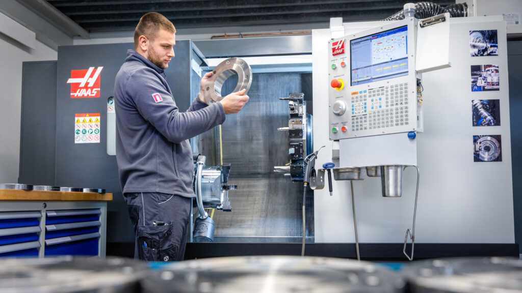 Mitarbeiter überprüft Qualität von CNC Bauteil